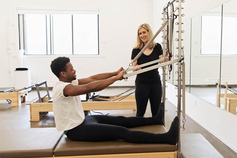 Pilates instructor teaching a private Pilates session to a male client in Montreal