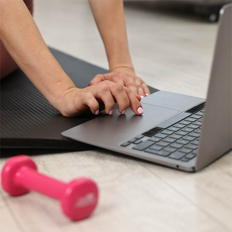 Woman setting up a computer to start a virtual Pilates class